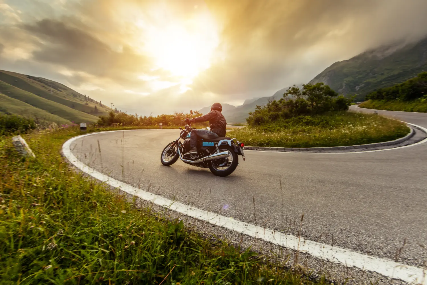 Motorradfahrer fährt in alpiner Landschaft.